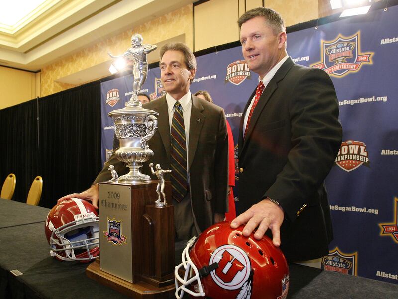 Utah head coach Kyle Whittingham, right, and Alabama coach Nick Saban pose with the Sugar Bowl Trophy.