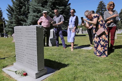 Wendy Fayles, mentor with the Utah chapter of the National Alliance on Mental Illness, takes a photo of a new granite marker memorializing those who died in the state’s first insane asylum following a dedication ceremony at the Salt Lake City Cemetery on