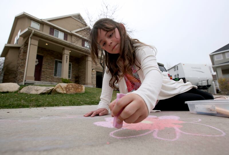 Eden Smith draws on the sidewalk outside of her home in Riverton, Utah, on Monday, April 8, 2019. The Smiths follow Dave Ramsey's cash-only envelope system.