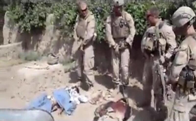 This image made on Thursday, Jan. 12, 2012 from undated video posted on the Internet on Wednesday, Jan. 11, 2012 by a YouTube user who identified themself as "semperfiLoneVoice" shows men in U.S. Marine combat gear, standing in a semi-circle over three bo