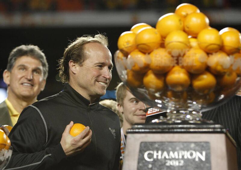 West Virginia's head coach Dana Holgorsen holds an orange following their victory in the Orange Bowl NCAA college football game, Wednesday, Jan. 4, 2012, in Miami. West Virginia defeated Clemson 70-33.