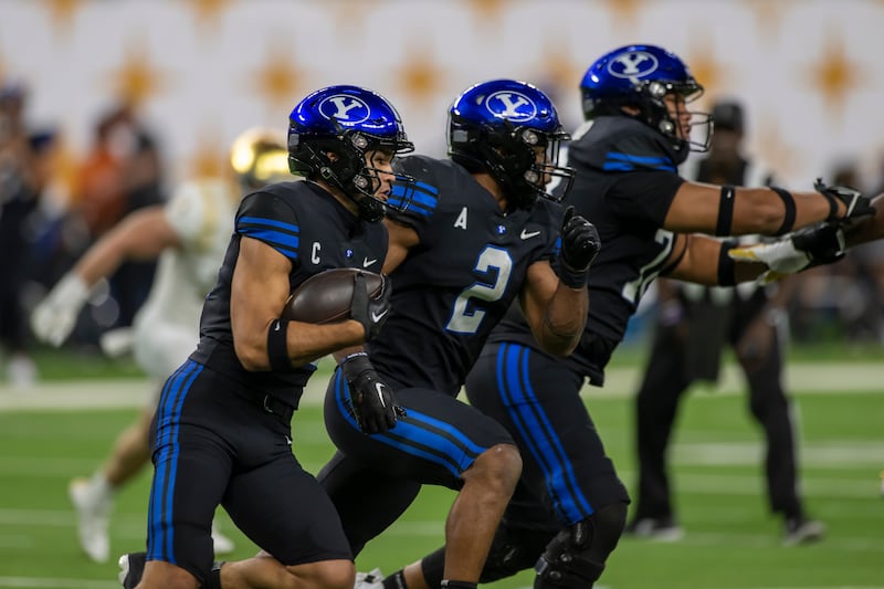 BYU receiver Puka Nacua, left, runs the football behind teammates Christopher Brooks (2) and Vae Soifua (73) in Las Vegas.