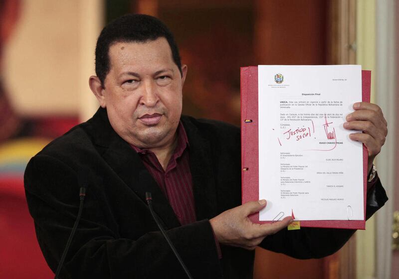 In this photo provided by Miraflores Presidential Press Office, Venezuela’s President Hugo Chavez shows a copy of a new labor law he just signed during a T.V. broadcast in Caracas,Venezuela, Monday April 30. 2012. Chavez signed a new labor law and said he