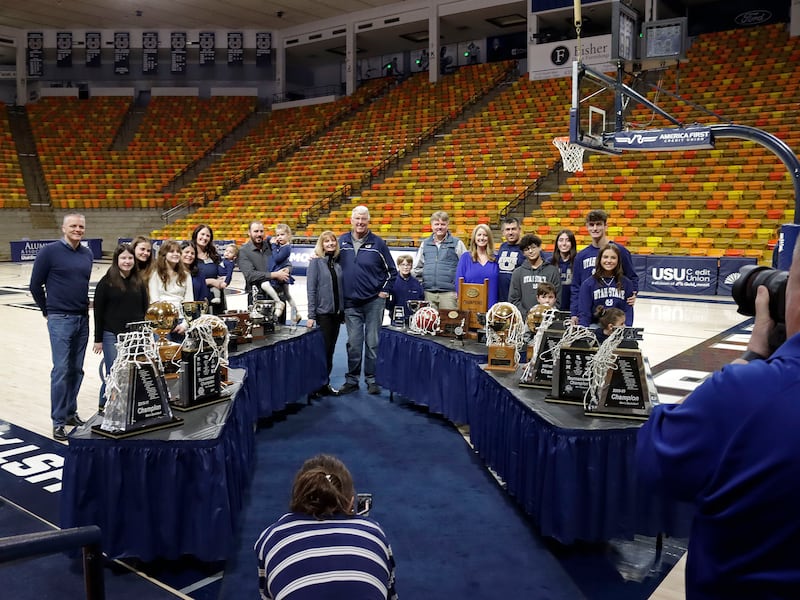 Stew and Vicki Morrill and their family pose for photos with trophies from Morrill’s coaching tenure at Utah State Friday night at the Spectrum in Logan.