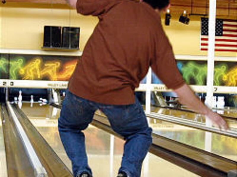 Guys \& Dolls member Shane Grahm demonstrates the art of leaning to urge the bowling ball to aim most effectively at the pins.