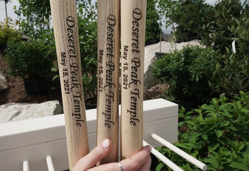 A closeup of the name and date printed on the handles of shovels for the Deseret Peak Utah Temple groundbreaking ceremony. They read “Deseret Peak Temple” in fancy script and “May 15, 2021” in a sans serif font beneath.