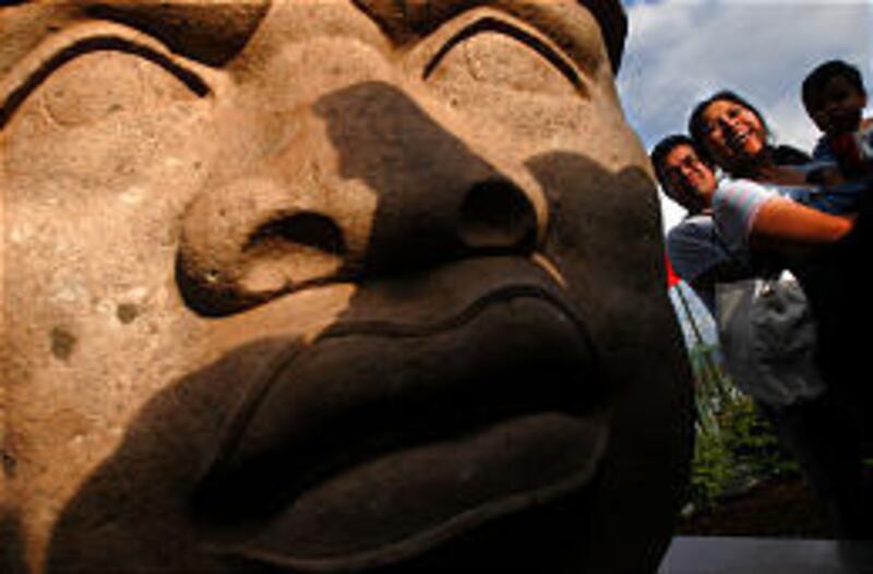 The Villareal family of Provo, Jared, left, his wife, Dely, and son, Jarzaih, gather around the Olmec head after its unveiling at the Utah Cultural Celebration Center in West Valley City. The head is a gift from Mexico.