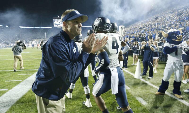Utah State Aggies head coach Matt Wells cheers his team at it enters the field in Provo Friday, Oct. 3, 2014.