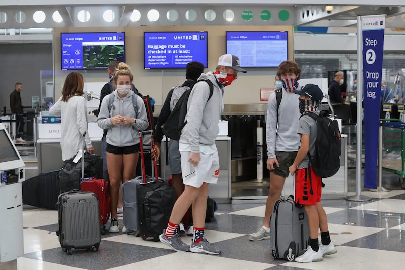 Travelers talk in a terminal at O’Hare International Airport in Chicago on Friday, Nov. 20, 2020. The recent weeks’ soaring numbers of coronavirus cases in Illinois prompted Gov. J.B. Pritzker to reimpose harsher restrictions on social interaction.