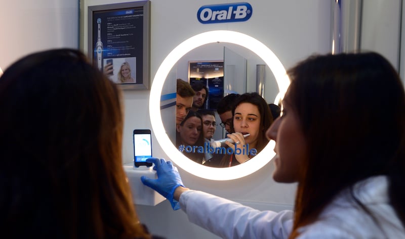 A woman uses an interactive electric toothbrush from Oral-B connected with a smartphone with Bluetooth at the Mobile World Congress, the world's largest mobile phone trade show in Barcelona, Spain, Wednesday, March 4, 2015.