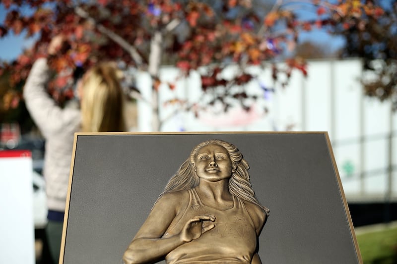 Robyn Kremer ties purple ribbons to a tree planted in honor of slain University of Utah student Lauren McCluskey.