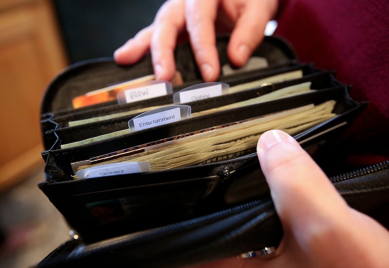 Sarah Smith shows the categorized wallet she uses to follow Dave Ramsey's cash-only envelope system at home in Riverton, Utah, on Monday, April 8, 2019.