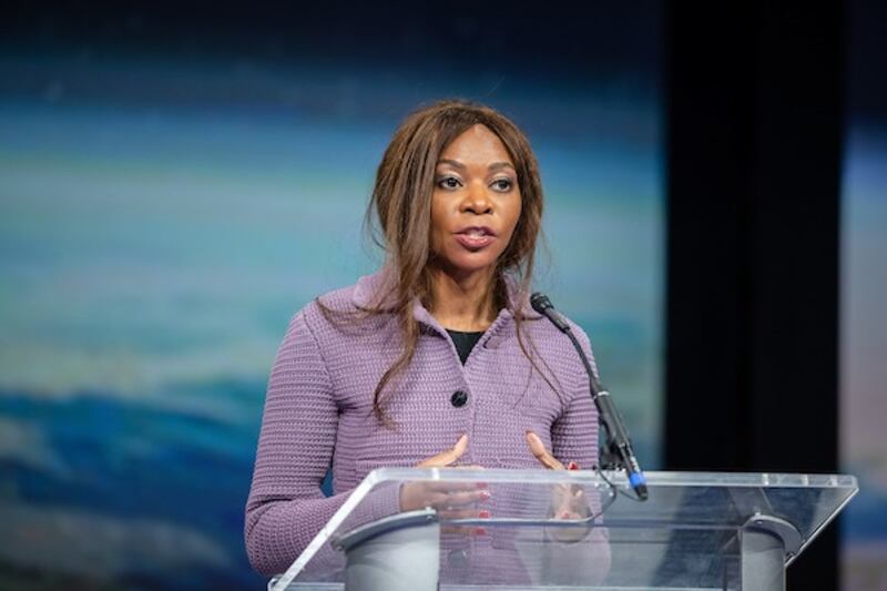 Economist Dambisa Moyo stands behind a lectern speaking to an audience at BYU in Provo, Utah.