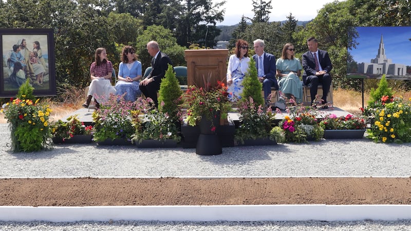 Elder James E. Evanson, a General Authority Seventy and member of the Church’s Canada Area presidency, third from left, talks with the youth speaker Vienna Wigg and pioneer speaker Marilyn Hall Terry before the groundbreaking ceremony of the Victoria British Columbia Temple on Saturday, Aug. 22, 2026, in Langford, British Columbia. Others on the stand are Graham and Lyanne Sanderson, co-chairs of the groundbreaking committee; Sister Jody Evanson, wife of Elder Evanson; and Elder M. Shayne Olsen, Area Seventy.