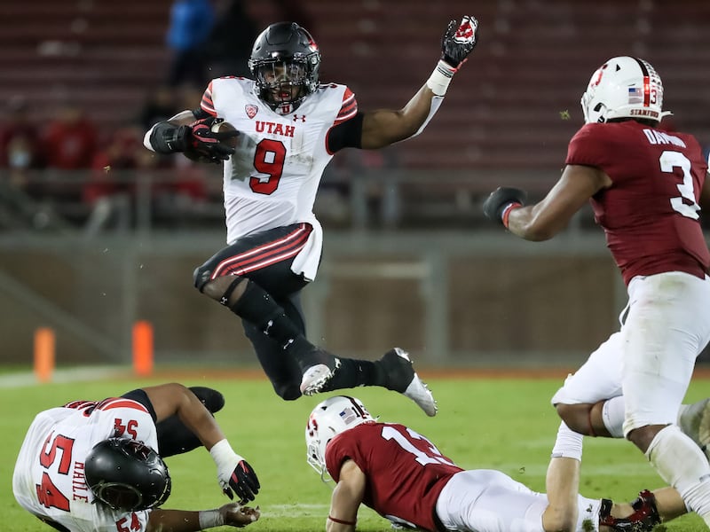 Utah Utes running back Tavion Thomas, wearing white, leaps over Stanford Cardinal cornerback Ethan Bonner (13)