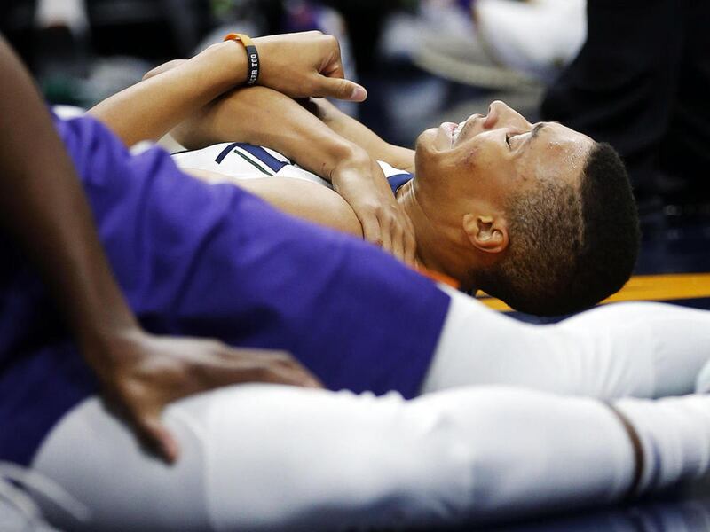 Utah Jazz guard Dante Exum holds his shoulder after hitting the floor during NBA basketball in Salt Lake City on Friday, Oct. 6, 2017. He was fouled by Phoenix Suns forward T.J. Warren.