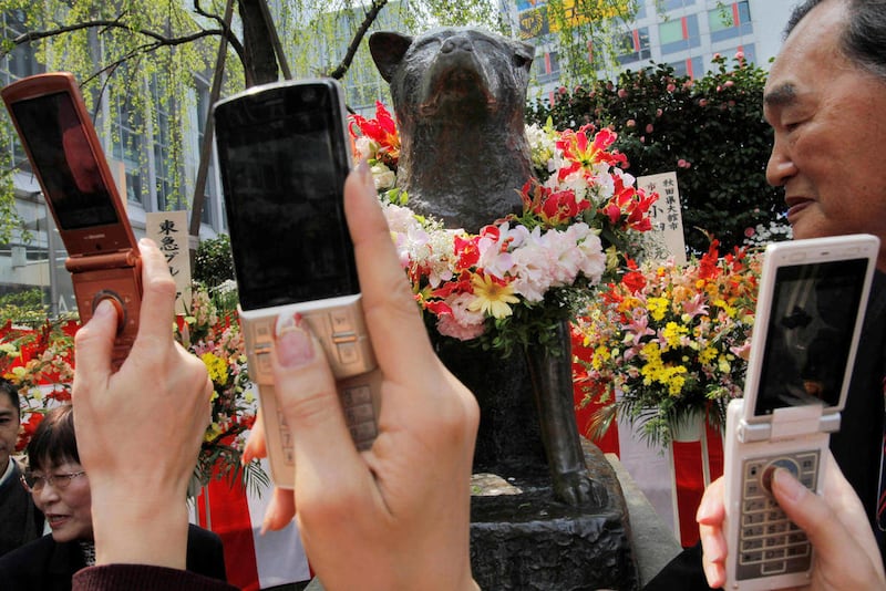 FILE - In this April 8, 2009 file photo, people take photos of a bronze statue of Japanese Akita dog "Hachi" during the 74th memorial service for the dog, intimately called Hachiko, in front of Shibuya railway station in Tokyo. He was rumored to have swal