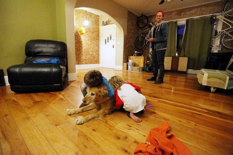 Nate Julian watches as sons Morrissey and Ander hug their dog, Bentley, at home in Salt Lake City on Tuesday, Oct. 10, 2017. Nate and his wife, Aliska, have decided to only have two children.