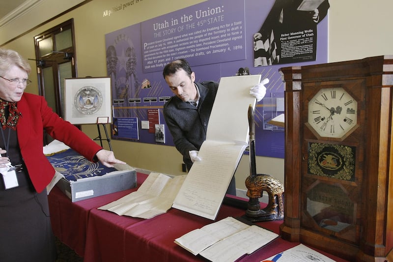 Judith McConkie points out the original Utah state Constitution being held by Ken Williams.