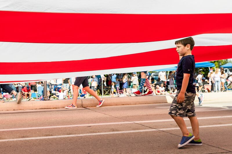 Carriers walk a large American Flag down the street at the Grand Parade in Provo on Tuesday, July 4, 2023.
