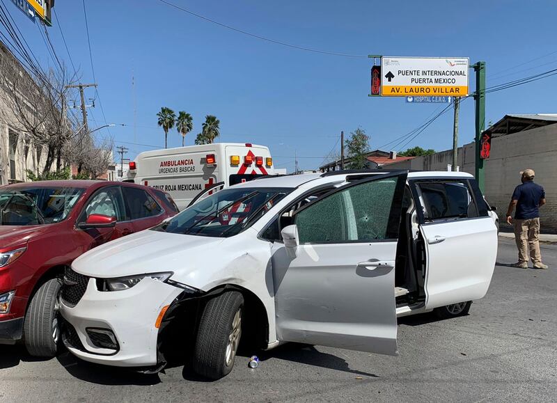 A member of the Mexican security forces stands next to a white minivan with North Carolina plates and several bullet holes.