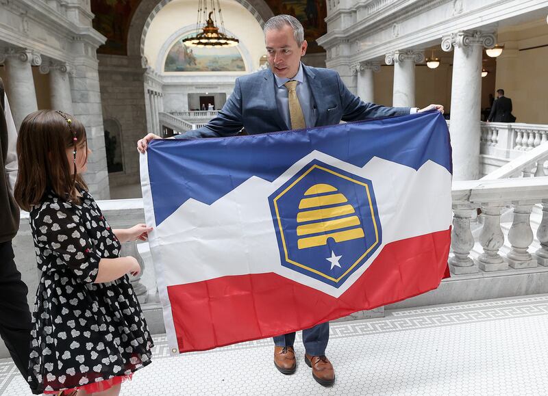 Savanna McCay helps her father, Sen. Daniel McCay, R-Riverton, hold the new Utah state flag at the Capitol on March 2, 2023.