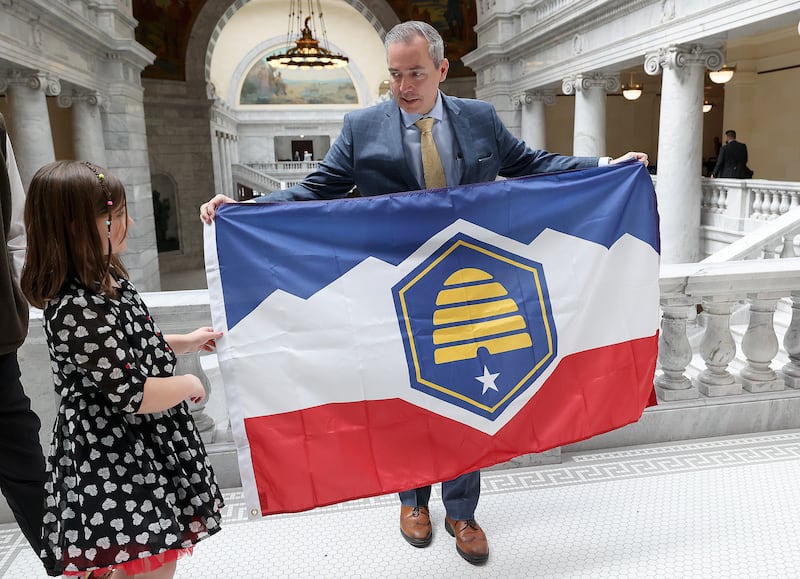 Savanna McCay helps her father, Sen. Daniel McCay, R-Riverton, hold the new Utah state flag at the Capitol on March 2, 2023.