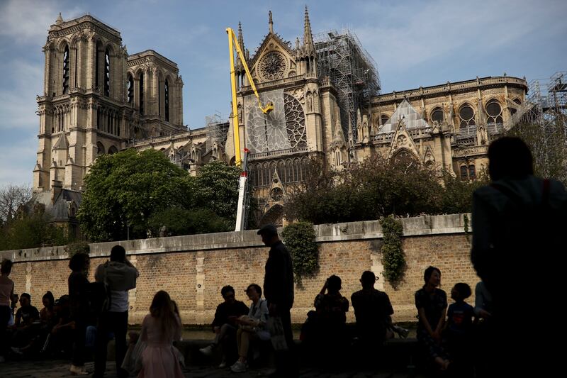 Workers, top, fix a net to cover one of the iconic stained glass windows of the Notre Dame Cathedral in Paris, Sunday, April 21, 2019. The fire that engulfed Notre Dame during Holy Week forced worshippers to find other places to attend Easter services, an