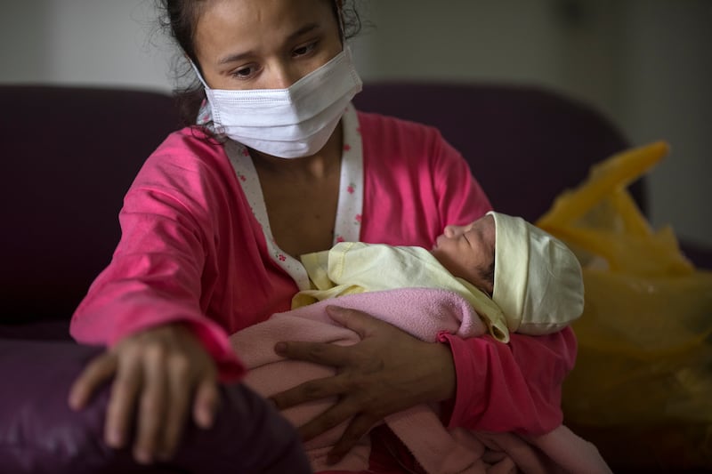Maria Alvarez, 24, sits on a sofa holding her 1-day-old daughter, in an isolated area reserved for mothers with COVID-19, at the National Maternal Perinatal Institute, in Lima, Peru, Thursday, July 30, 2020. Alvarez faces the burden of raising her daughter on her own because the baby’s father died of the new coronavirus in June.
