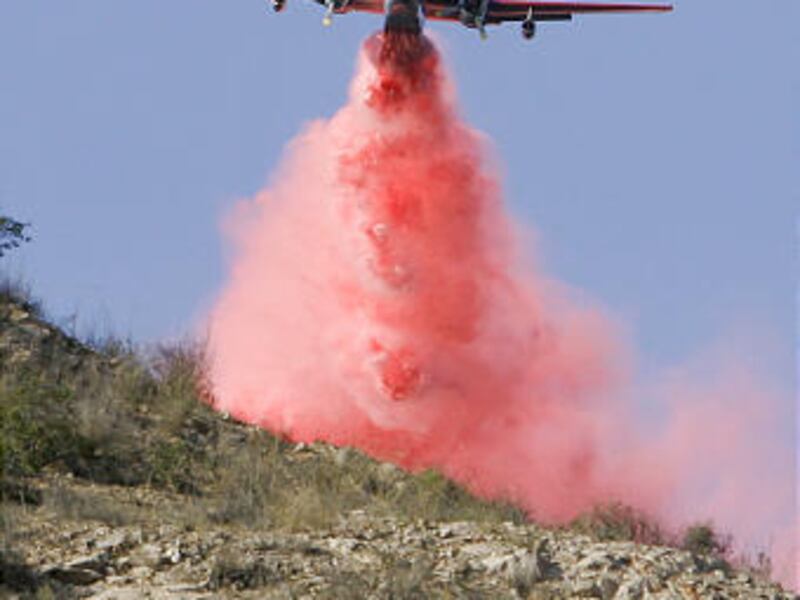 An air tanker drops fire retardant near homes where a wildfire driven by powerful Santa Ana winds threatened homes, Monday in Malibu, Calif.