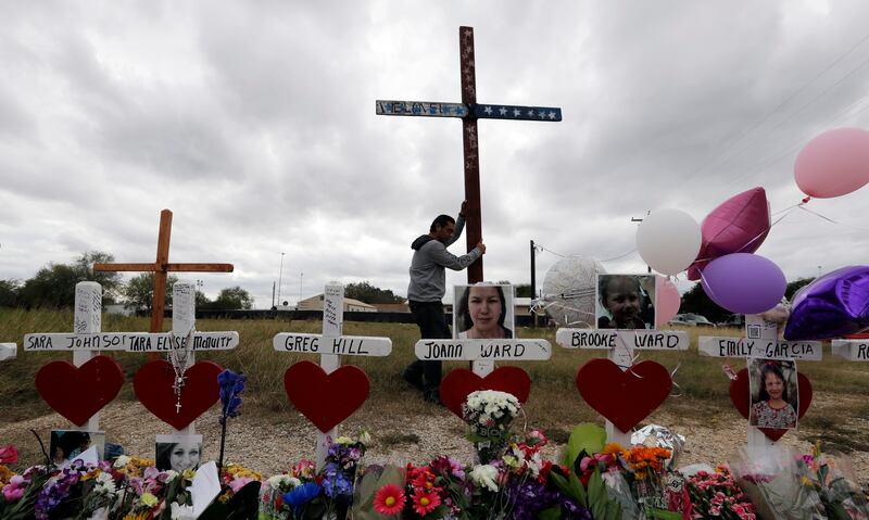 Miguel Zamora stands a cross for the victims of the Sutherland Springs First Baptist Church shooting at a makeshift memorial.
