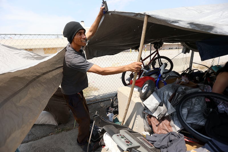 A homeless man who only gave the name Abdul sets up a tarp for shade during a heat wave in Salt Lake City on July 12, 2021.