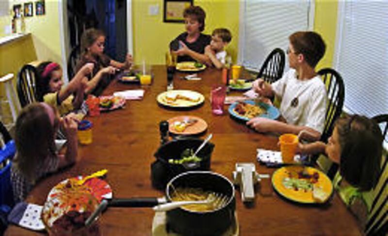Carmen Staicer, center, the mother of two boys and four girls, eats dinner with her children, from left, Riley, Emma, Allegra, Gabriel, Nikolas and Mackenzie, at their home in Virginia Beach, Va.