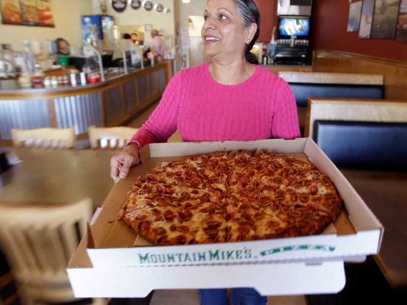 Woman holds a pepperoni pizza.