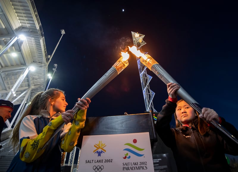 Gabrielle Harris and YiYi O’Brien combine torches marking the 20th anniversary of the 2002 Winter Games.