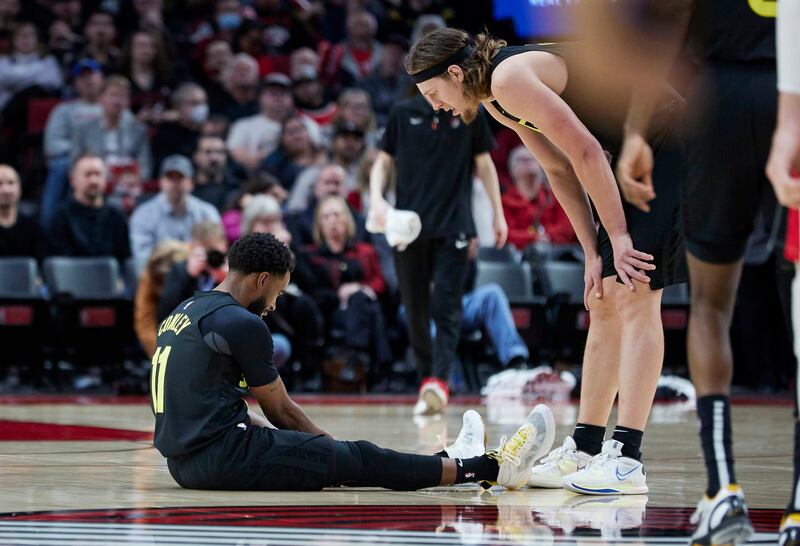 Utah Jazz forward Kelly Olynyk, right, talks to guard Mike Conley, who sits on the court after being injured vs. Portland.