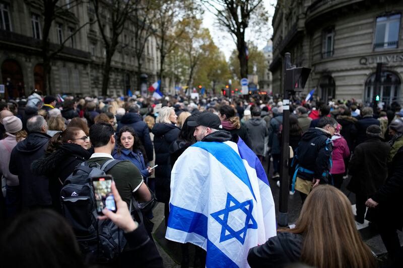 A demonstrator wearing an Israeli flag joins thousands other people for a march against antisemitism in Paris, France, Sunday, Nov. 12, 2023.