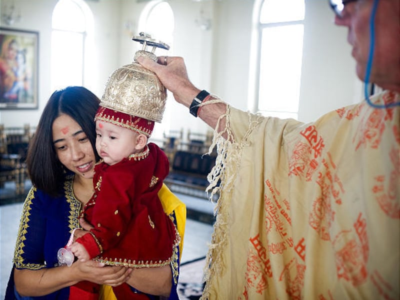 Caru Das conducts a ritual for a mother and daughter at the Hare Krishna temple.