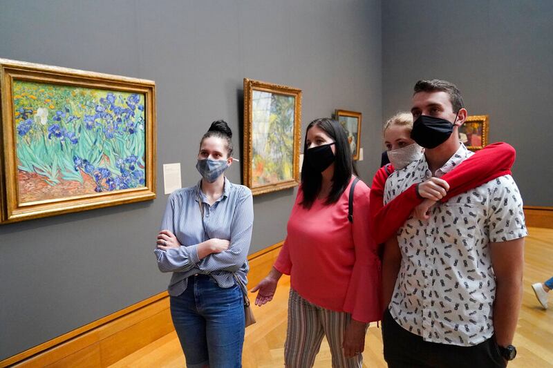 Visitors wear masks as they view Vincent van Gogh’s “Irises.”