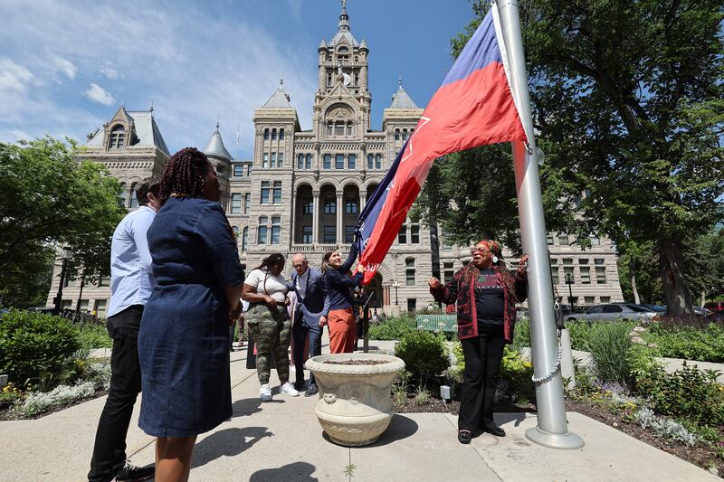Leaders from the Black community, City Council, law enforcement and the state take turns raising the Juneteenth flag.