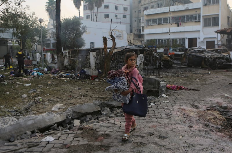 A Palestinian girl walks past the site of a deadly explosion at al-Ahli hospital, in Gaza City on Oct. 18, 2023.
