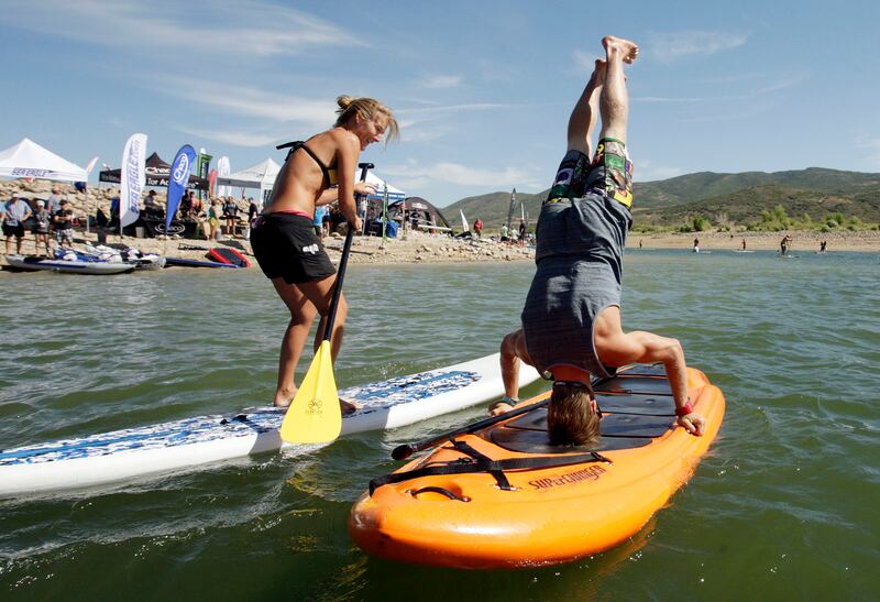 Nick Troutman does a head stand as Kathy Summers watches during the Outdoor Retailer’s Open Air Demo at Jordanelle State Park.