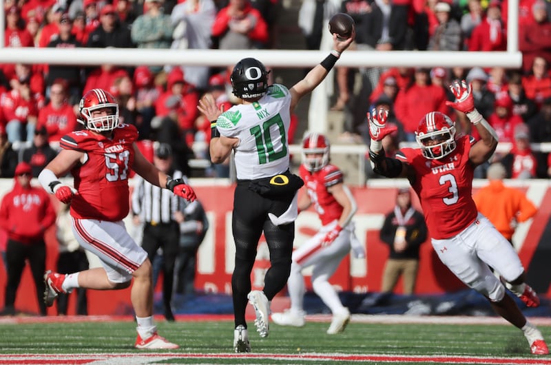 Utah defensive tackle Keanu Tanuvasa (57) and and linebacker Levani Damuni (3) get pressure on Oregon quarterback Bo Nix.