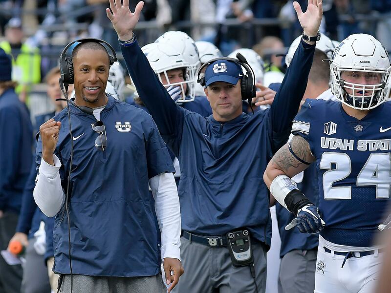 Utah State receivers coach Jovon Bouknight, left, and coach Matt Wells celebrate a touchdown against UNLV during an NCAA college football game Saturday, Oct. 13, 2018, in Logan, Utah.