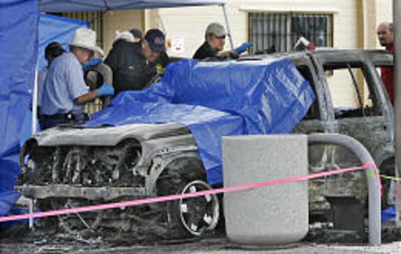 Officials inspect a car where a father and his two children were found burned in the back seat of their vehicle at a gas station on Skull Valley Reservation.