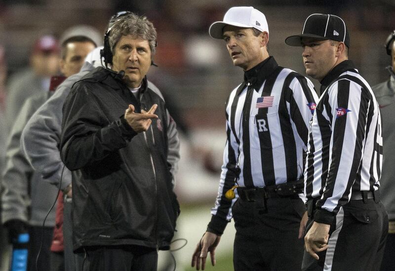 Washington State head coach Mike Leach, left, asks referee Land Clark, center, and head linesman Bart Longson, right, a question during the first half of an NCAA college football game against Arizona State, Thursday, Oct. 31, 2013, at Martin Stadium in Pu