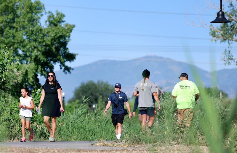 People walk in Pioneer Crossing Regional Park in West Valley on July 20, 2023.