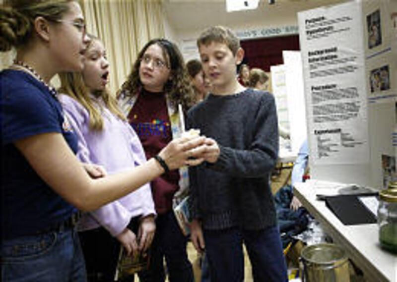Weylin Oakes hands McCall Blake a cup of ice cream, part of the Mars experiment at the science display at Wasatch Elementary in Provo.