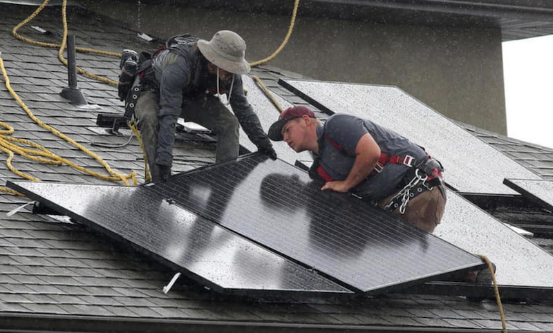 FILE: Workers install solar panels on a home in Lehi on Tuesday, May 17, 2016.