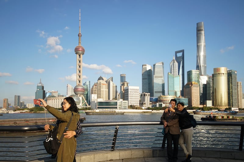 People take selfies of the Pudong skyline as they stand on the Bund in Shanghai, China.
